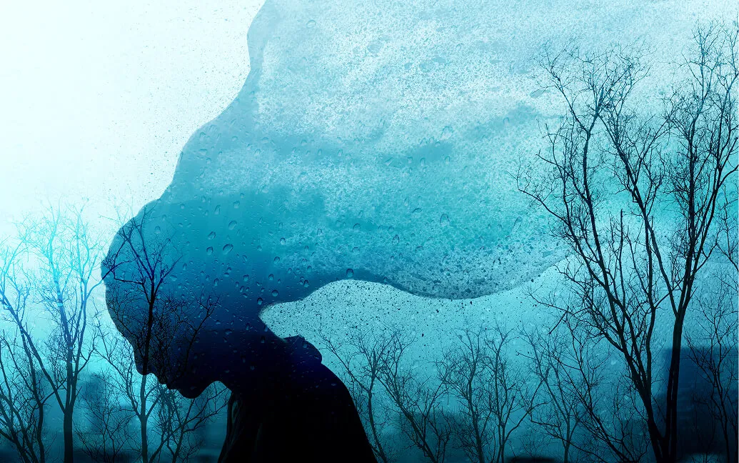 Artistic blue-toned image blending a person’s silhouette with water and bare winter branches